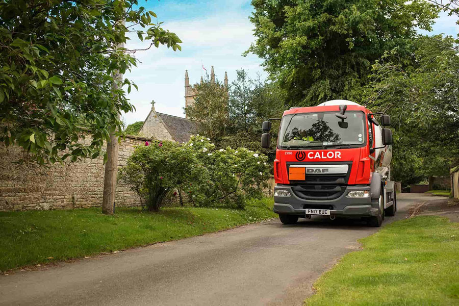 A front view of a Calor lorry driving through a village